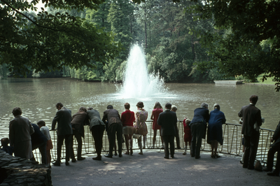 119386 Afbeelding van enkele toeschouwers bij de fontein in de vijver van het Julianapark te Utrecht.